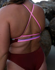 Close up view of the JAYD Swimwear full bum coverage Airlie one piece in cinnamon with contrasting cross-over fairy floss back straps and a lilac haze middle back strap.