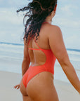 JAYD models Madi spinning around on a beach wearing the flattering Albi one piece swimsuit in vibrant Blaze red.