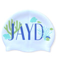 White swim cap with 'JAYD' logo and underwater-themed blue and green corals, fish and shells.