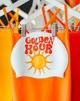 Orange swimsuit with 'Golden Hour' text and sun graphic on a rack.