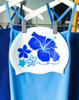 Four tropical blue flowers illustrated on a white swim cap with the JAYD Swimwear 'dive in with confidence' signature phrase.