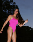 Athlete Jenaya modelling the JAYD Swimwear Isla one piece in pink sorbet underneath a full moon at night.