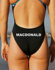 Person wearing a black swimsuit with custom name branding on the backside.