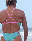 Lucy Derbyshire wearing the Seamist Lennox one piece with pastel Fairy Floss contrasting straps at the beach, showcasing JAYD’s mid-coverage chlorine-resistant swimsuit for swimmers and ocean athletes.