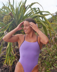 Ocean athlete, Lucy Derbyshire, trains and races in the JAYD Swimwear Zambia swimsuit featuring a Lilac Haze body with bold Açaí contrasting straps and cutouts.