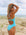 Side view of model on beach wearing Airlie One Piece Athletic Swimsuit in Mykonos Blue by JAYD Swimwear.
