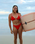 Ski paddler Jenaya Massie on a moarning surf at Kirra beach wearing the JAYD Swimwear Ruby Connie Bottoms and Ruby Triangle Top.