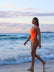 Side shot of model on a beach wearing JAYD Swimwear Ibiza one piece in Neon Orange.