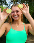 Cheeky image of Soraya holding limes wearing JAYD Swimwear tie back athletic full coverage one piece: Riva in Meadow
