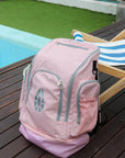 Pale pink JAYD Swimwear Backpack sitting on pool deck.