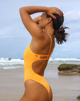 Side view of model on the beach wearing JAYD Swimwear athletic Zimmy one piece in colour shade Sunshine.