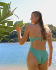 Rear standing view of JAYD Swimwear's full-coverage athletic one-piece Airlie in the shade Matcha.