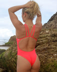 Back view of model on the beach wearing JAYD Swimwear athletic Finley one piece in colour shade Fiesta.