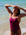 Front view of model on a beach wearing JAYD Swimwear athletic one piece Tallow in Sangria.