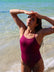 Front view of model on a beach wearing JAYD Swimwear athletic one piece Tallow in Sangria.
