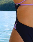 Close hip view of model on beach wearing JAYD Swimwear athletic one piece swimsuit Zambia in Acai.