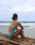 Back view of model on the beach wearing JAYD Swimwear athletic Zimmy one piece in colour shade Mykonos blue.