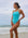 Front view of model on the beach wearing JAYD Swimwear athletic Zimmy one piece in colour shade Mykonos blue.