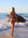 Back view of model on beach wearing JAYD Swimwear cheeky bikini bottom Demi in Fairy Floss Pink.