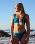 Front view of model on beach wearing JAYD Swimwear cheeky bikini bottom Demi in Nordic Blue.