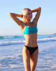 Front view of model on a beach wearing JAYD Swimwear athletic bikini top torquay in Atlantic Green.