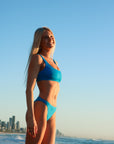 Front view of model wearing JAYD Swimwear athletic bikini top Nalu in Cancun Blue.