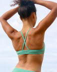 Back strap view of model wearing JAYD Swimwear athletic Torquay training bikini top in Matcha green.