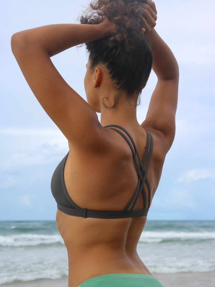 Back strap view of model wearing JAYD Swimwear athletic Tazzie training bikini top in Carbon.