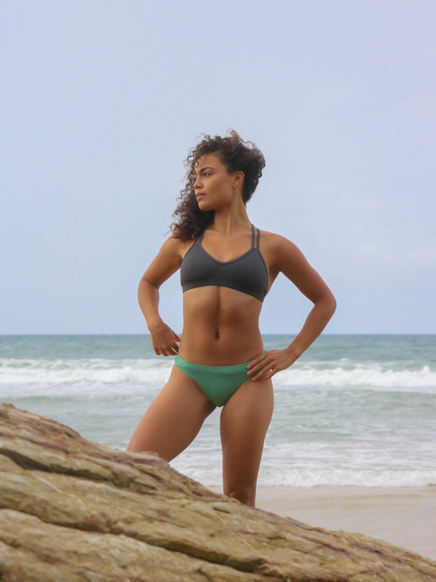 Front view of model wearing JAYD Swimwear athletic Tazzie training bikini top in Carbon.