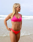 Front view of model wearing JAYD Swimwear athletic Tazzie training bikini top in Pink Sorbet.