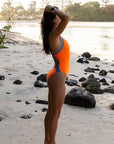 JAYD Swimwear triathlete Ana wears the fixed back Lennox one piece in the colour Neon Orange with contrasting Cancun hip cut outs and straps. This piece offers mid coverage and sits high on the hips, elongating the legs.