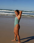 JAYD Swimwear fixed back one piece called Lennox. Worn by athlete Sara in the Matcha colour with fairy floss straps and hip detailing.