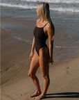 Keira wears the Albi one piece in Cacao, standing on the beach in Gold Coast Australia. One piece is chlorine resistant