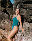 Woman in a cove JAYD one piece standing on rocky terrain