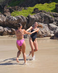 Athletes Molly & Madi frolic along the beach in the JAYD Ibiza One Piece in Black x Pink Sorbet and Orchid x Sangria, the perfect competition & lifestyle hybrid swimsuit.