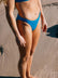 Brodee wears the Cali mid-coverage bottom in Cancun blue on a sandy beach