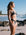 Woman in a Carbon grey bikini standing on a beach with ocean and sky in the background. She wears the Triangle top and Cali bottom