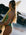 Woman in a Moss green JAYD Swimwear "Tallow" one piece holding a surfboard on a beach