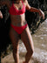 Madi wears the Connie full-coverage bottom in Fiesta, standing by a rocky shoreline.