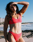 JAYD Ambassador Madi wears JAYD Fiesta coloured bikini standing on a beach with ocean and sky in the background.