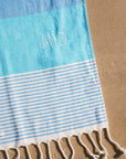 JAYD Swimwear Laguna towel, Woven as a Turkish pestemal with a soft terry back, quick drying, compact and cute with a pattern of contrasting shades of blue.