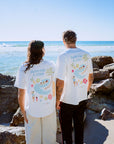 Two people standing on a rocky beach wearing matching t-shirts Swim For A Cure fundraiser t-shirts.