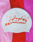 White swim cap with cursive JAYD Swimwear text and red and pink cherry disco balls.