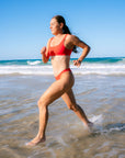 Triathlete Charlotte Derbyshire putting the Nalu Bikini Top to the test as she runs through shallow water along the beach.