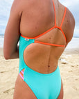 Close up of the Zambia JAYD one piece in seamist blue with contrasting flare orange shoulder straps and pink and orange hip cut-outs.