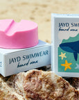 Pink surf wax with close up of JAYD Swimwear packaging.