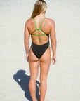 JAYD model showcasing the mid coverage Zambia one piece with black swimsuit body and contrasting moss cross-back shoulder straps.