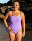 Athlete Kimberley Doyle wearing the JAYD Swimwear Zambia lilac haze x fairy floss one piece on the beach at sunrise.