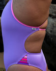 Close up side view of the JAYD Swimwear Zambia one piece in lilac haze with fairy floss straps and contrasting pink and purple hip details.