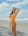 JAYD model Charlotte showcasing the cheeky high-cut hip design of the Zimmy one piece in Flare orange, which elongates the legs and creates a long, lean silhouette so you can dive in with confidence and finesse.